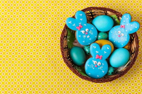 Pierniczki Wielkanoc królików, żółty i niebieski z kurczaka i przepiórcze jaja w wiklinowym koszu, widok z góry — Zdjęcie stockowe