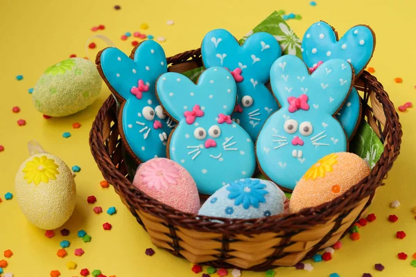 Easter funny rabbits, homemade painted gingerbread biscuits in glaze on a yellow background, Top view
