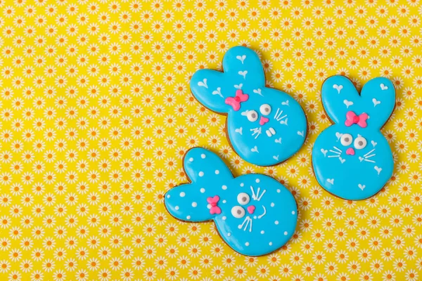 Easter funny rabbits, homemade painted gingerbread biscuits in glaze on a yellow background