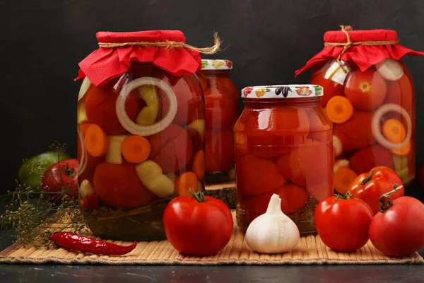 Plusieurs pots de tomates sont situés sur une table, sur un fond sombre — Photo