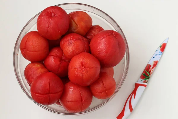 Очищенные помидоры с разрезами, расположенными в миске на белом фоне — стоковое фото
