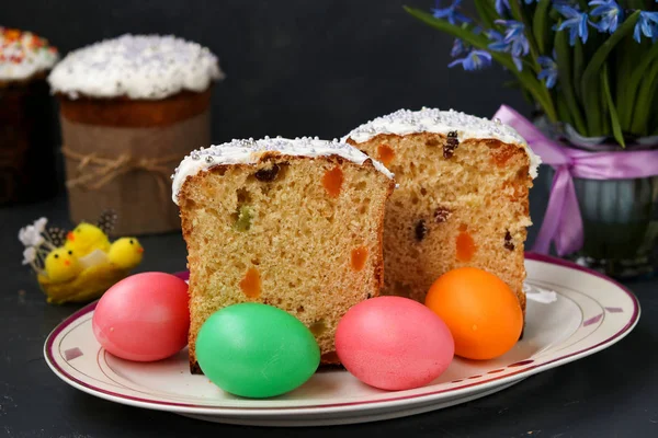 Gâteaux de Pâques et des œufs colorés sont situés sur une assiette sur un fond sombre — Photo