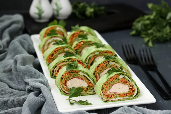 Rouleau de lavande avec bâtonnets de crabe, épinards, persil et carottes à la coréenne sur une assiette sur un fond sombre — Photo