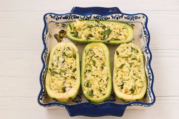 Zucchini diisi dengan keju yang disiapkan untuk dipanggang yang terletak dalam bentuk keramik pada latar belakang putih — Stok Foto