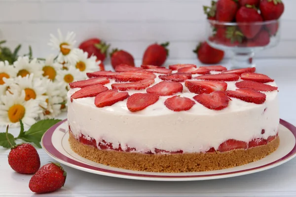 Un tort cu căpșuni fără coacere, cu o bază de biscuiți, este plasat orizontal pe o farfurie pe un fundal alb — Fotografie, imagine de stoc