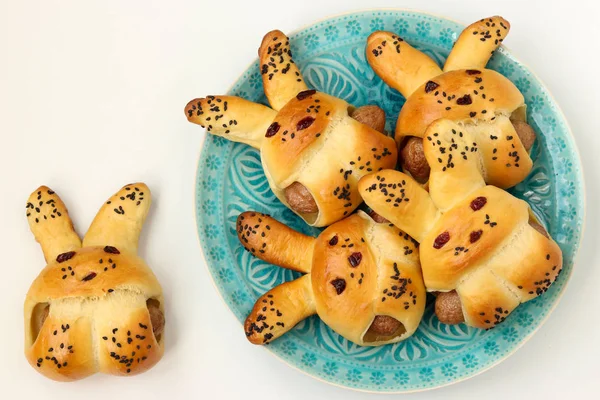 Haas vormige broodjes met worstjes voor kinderen gelegen op een blauwe plaat op een witte achtergrond, een culinair idee voor kinderen — Stockfoto