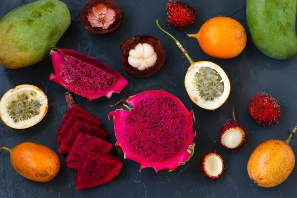 Tropical fruits: dragon fruit, passion fruit, mangosteen, rambutan and mangoes are located on a dark background