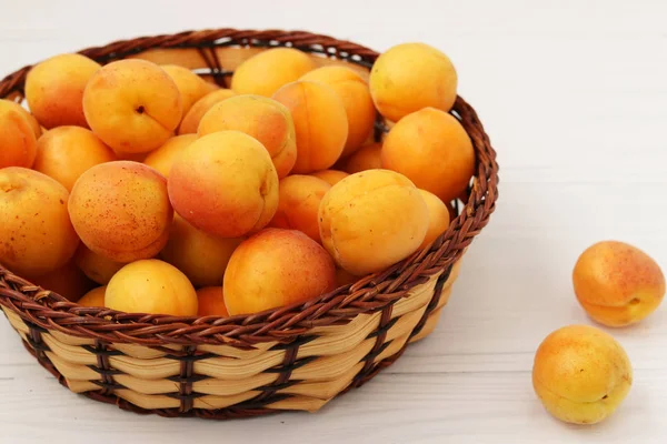 Ripe apricots are located in a wicker basket on a white background — Stock Photo, Image