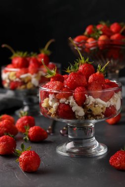 Koyu bir arka plan karşı cam kadehler çilek, süzme peynir ve bisküvi ile Tatlı