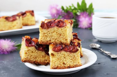 Tabaktaki erik turtası dilimleri koyu bir arka planda yer alır.