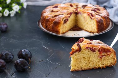 Erik pasta karanlık bir arka plan üzerinde bir tabak üzerinde yer almaktadır, ön planda kek parçası, Taze erik masada