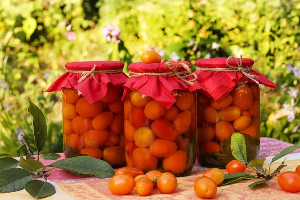 Мариновані вишневі помідори в банках на столі в саду — стокове фото
