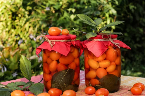 Tomates cherry marinados en frascos sobre una mesa en el jardín — Foto de Stock