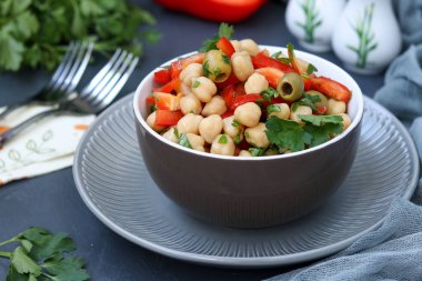 Sağlıklı nohut salatası, yeşil zeytin, biber ve maydanoz, koyu bir arka plan üzerinde yer almaktadır
