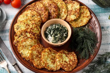 Kabak börek bir tabak üzerine serilir, merkezinde sarımsak ve dereotu ile ekşi krema sosu var