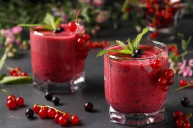 Koyu bir arka plan üzerinde gözlük siyah ve kırmızı kuş üzümü ile Smoothies