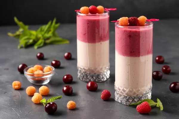 Smoothies mit Beeren aus gelben Himbeeren und Kirschen in Gläsern auf dunklem Hintergrund — Stockfoto