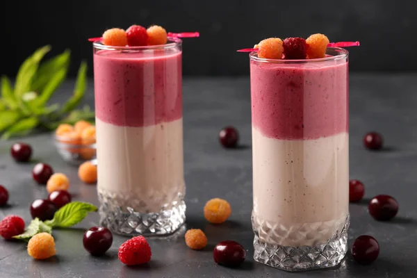 Smoothies mit Beeren aus gelben Himbeeren und Kirschen in Gläsern auf dunklem Hintergrund — Stockfoto