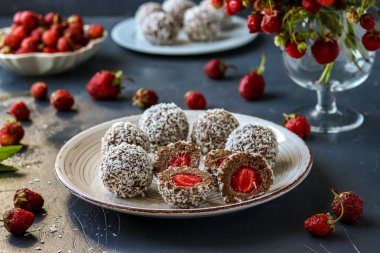 Hindistan cevizi talaş, çilek ve çikolatalı kurabiye koyu bir arka plan üzerinde bulunan, yatay ile lor topları