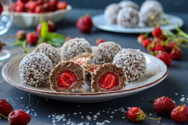 Hindistan cevizi talaş, çilek ve çikolatalı kurabiye koyu bir arka plan üzerinde bulunan, yatay ile lor topları