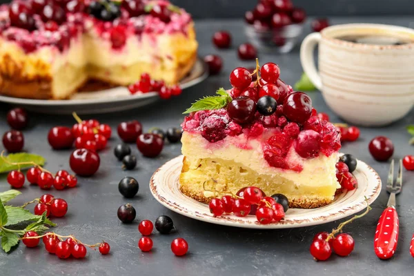 Летний творожный торт с ягодами расположен на темном фоне, на переднем плане кусок торта на тарелке, горизонтальное фото — стоковое фото