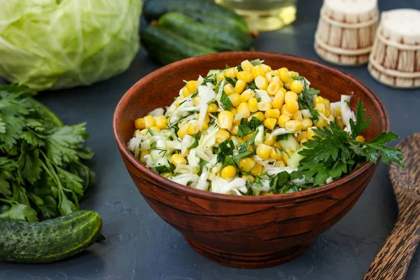 Здоровый салат с капустой, огурцами, кукурузой и петрушкой в салатной чашке на темном фоне, горизонтальное фото — стоковое фото