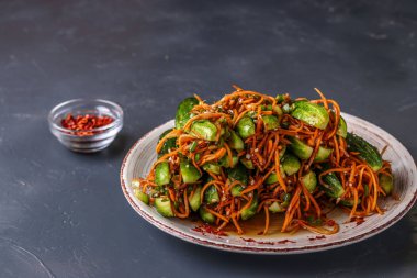 Traditional Korean cucumber kimchi snack: cucumbers stuffed with carrots, green onions, garlic and sesame, fermented vegetables, horizontal photo clipart