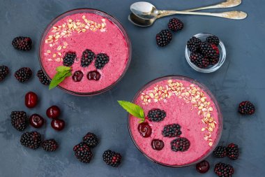Siyah zemin, yatay fotoğraf, üst görünüm üzerinde böğürtlen, kiraz ve yulaf ezmesi ile Sağlıklı kahvaltı smoothie kase