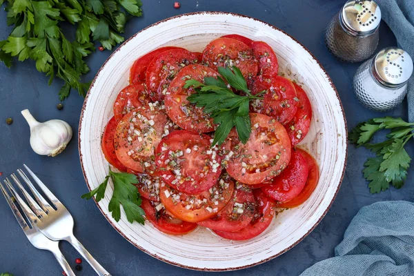 Sarımsak, maydanoz ile domates vejetaryen meze, bal ve zeytinyağı ile koyu bir arka plan üzerinde bir tabak ta bulunan giyinmiş, yatay fotoğraf, üst görünümü — Stok fotoğraf