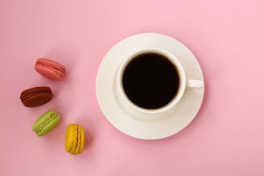 Kahve fincanı ve pembe arka planda renkli fransız makaroları, Üstte görünüm, Boşluk fotokopisi, yatay fotoğraf
