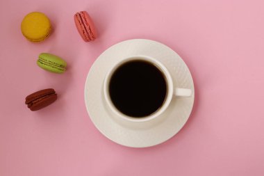 Kahve fincanı ve pembe arka planda renkli fransız makaroları, Üstte görünüm, Boşluk fotokopisi, yatay fotoğraf