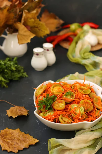 Корейский салат с зелеными помидорами и морковью в белой салатной миске на темном фоне, вертикальное фото — стоковое фото
