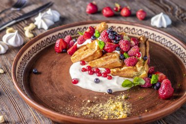 Ahşap bir masada bir plaka içinde Berry salsa ve krem peyniri ile ev yapımı waffle, yatay fotoğraf
