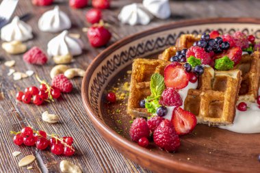 Ahşap bir masada bir plaka içinde Berry salsa ve krem peyniri ile ev yapımı waffle, yatay fotoğraf