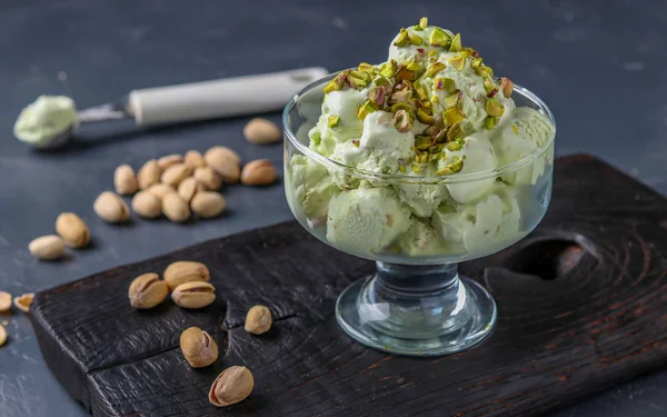 Helado de pistacho con pistachos tazón de helado de vidrio sobre un fondo oscuro, foto horizontal — Foto de Stock