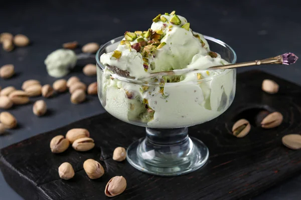 Pistachio ice cream with pistachio nuts glass ice-cream bowl on a dark background, horizontal photo