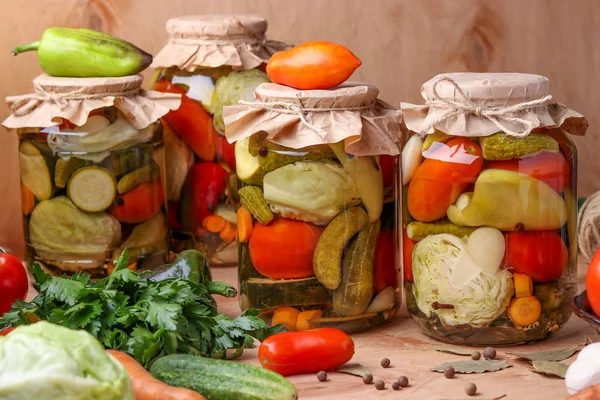 Rozmanená nakládané zelenina ve skleničkách: okurky, rajčata, zelí, cuketa a papriky s česnekem, Dill a zálivem v skleničkách na dřevěné pozadí, rustikální styl — Stock fotografie