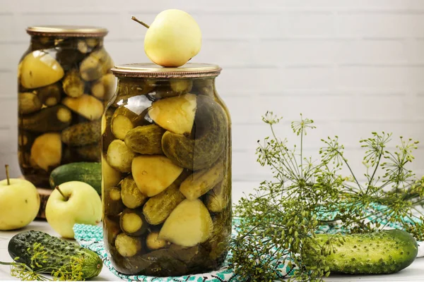 Concombres marinés avec des pommes dans des pots sont disposés sur un fond blanc, Récolte pour l'hiver, gros plan, photo horizontale, espace de copie — Photo