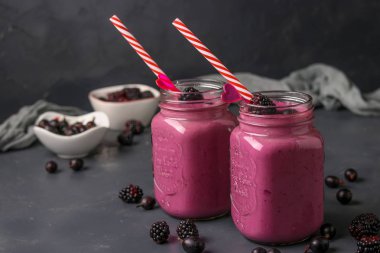 Koyu bir arka plan üzerinde cam böğürtlen ve bektaşi üzümü ile Smoothies, yatay düzenleme