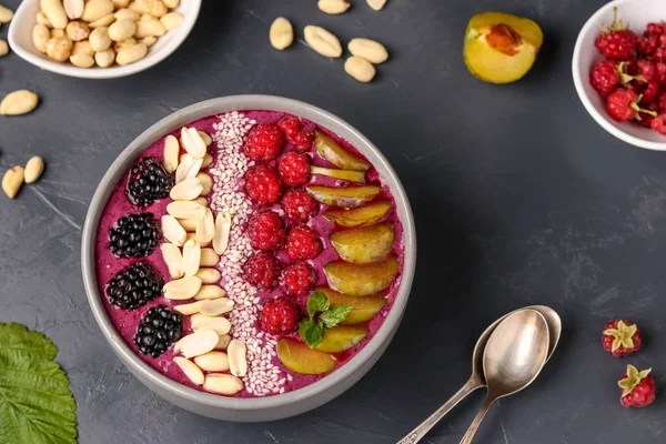 Siyah bir arka plan üzerinde böğürtlen, erik, ahududu, yer fıstığı ve susam ile Sağlıklı kahvaltı smoothie kase, yatay fotoğraf