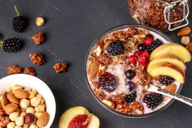 Doğal yoğurt, taze çilek ve meyve, çikolata ve fındık ile granola gevrek bal müsli koyu bir arka plan, yatay yönelim, üst görünümü karşı cam bir kase içinde