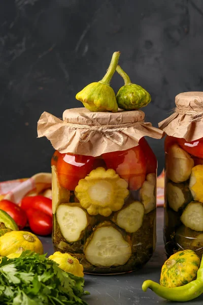 Surtido de pepinos en escabeche, patissons y tomates en frascos sobre un fondo oscuro, orientación vertical —  Fotos de Stock