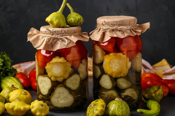 Surtido de pepinos en escabeche, patissons y tomates en frascos sobre un fondo oscuro, orientación horizontal —  Fotos de Stock