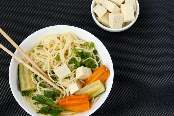 Supă asiatică tradițională cu brânză tofu, tăiței, morcovi și dovlecei pe fundal întunecat. Acest fel de mâncare conține de obicei bouillon și legume, vedere de sus, spațiu de copiere — Fotografie, imagine de stoc