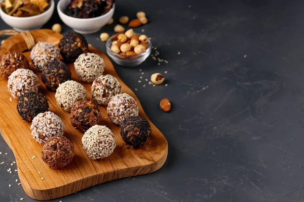 Boules énergétiques de noix, flocons d'avoine et fruits secs sur panneau de bois sur fond sombre, orientation horizontale, espace de copie — Photo