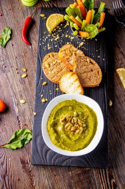 Ahşap bir tahta ve bruschetta, oryantal ve Arap mutfağı, dikey oryantasyon üzerinde bir kase içinde ıspanak, avokado ve kabak çekirdeği ile Humus