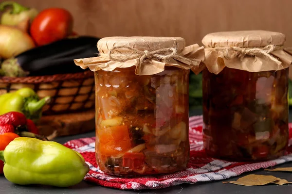 Biber, patlıcan, soğan ve domates ile sebze salatası ahşap bir masa üzerinde kavanoz, yatay oryantasyon
