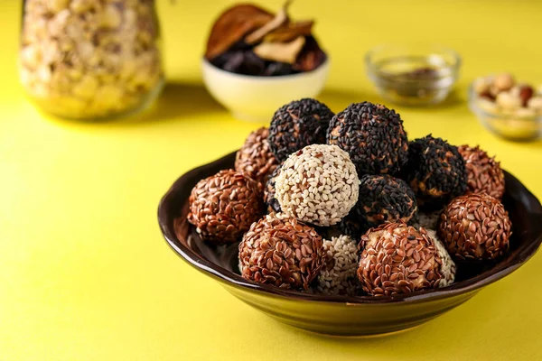 Bolas e ingredientes energéticos: frutos secos, avena y frutos secos en un plato sobre fondo amarillo, orientación horizontal — Foto de Stock