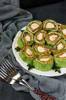 Koyu bir arka plan, dikey yönelim karşı bir tabak üzerinde Yengeç çubukları, ıspanak, maydanoz ve havuç Kore tarzı nda Lavaş rulo