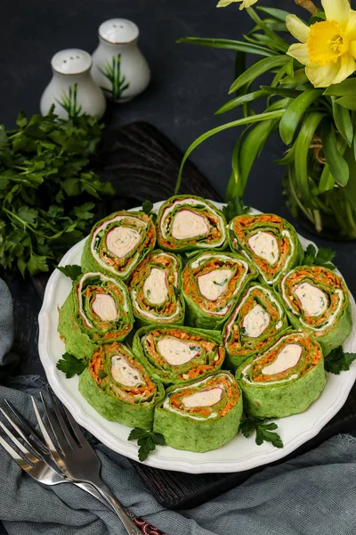 Rollo de lavash con palitos de cangrejo, espinacas, perejil y zanahorias en estilo coreano en un plato sobre un fondo oscuro, orientación vertical, primer plano — Foto de Stock